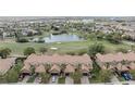 Aerial view of townhomes with golf course and pond featuring tile roofs and brick driveways at 10731 Belfry Cir, Orlando, FL 32832