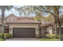 Charming townhome featuring a brick driveway, two-car garage, and stone accents, surrounded by lush greenery at 10731 Belfry Cir, Orlando, FL 32832