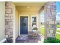 Inviting front porch with stone columns, elegant door, and charming decor at 1107 Trappers Trail Loop, Davenport, FL 33896