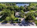 An aerial view showcases the home's proximity to a tranquil lake surrounded by verdant trees at 1444 Pelican Bay Trl, Winter Park, FL 32792