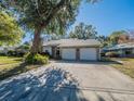 Home featuring a two-car garage and mature landscaping along with a large tree at 1444 Pelican Bay Trl, Winter Park, FL 32792