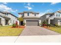 Attractive two-story home showcasing a paver driveway, manicured lawn, and modern architectural details at 1565 Leaf Ln, Kissimmee, FL 34744
