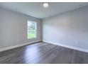 Bright bedroom with wood-look flooring, neutral walls, and a large window overlooking the lawn at 1706 3Rd Ave, Deland, FL 32724