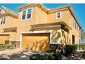 Two story tan home featuring a two car garage, manicured landscaping, and a stone facade on the bottom of the house at 17459 Chateau Pine Way, Clermont, FL 34711