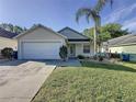 Well-maintained home with a two-car garage, lush front lawn, and mature palm trees, showcasing curb appeal at 2316 Paulette Dr, Haines City, FL 33844