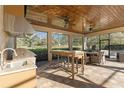 Covered outdoor kitchen with stainless steel appliances, bar seating, and serene views of the property at 2515 Ridgewind Way, Windermere, FL 34786