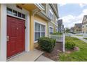 Close up of a colorful townhome featuring a red front door, manicured landscaping and white trim at 2604 Lodi Cir # 103, Kissimmee, FL 34746