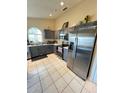Modern kitchen featuring gray cabinets, stainless steel appliances, and ample counter space with an arched window at 2678 Autumn Creek Cir, Kissimmee, FL 34747
