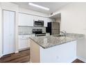 Modern kitchen with stainless steel appliances, granite countertops, and white cabinetry at 4105 Tropical Isle Blvd # 222, Kissimmee, FL 34741