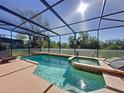 Screened-in pool and spa with clear blue water, surrounded by a spacious deck area at 802 Suffolk Pl, Davenport, FL 33896