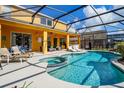 Sparkling screened-in pool with a jacuzzi, poolside lounge area, and sunny skies at 917 Orange Cosmos Blvd, Davenport, FL 33837