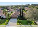 Aerial shot showcasing a beautiful home with a tile roof, a long driveway, and a well-manicured lawn at 10986 Ledgement Ln, Windermere, FL 34786