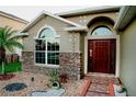 Inviting home exterior showcasing stone accents, arched windows, a dark wood front door, and decorative landscaping at 2224 Paria Ln, Kissimmee, FL 34758