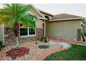Front yard featuring a beautiful palm tree, decorative stone landscaping and a colorful walkway to the entrance at 2224 Paria Ln, Kissimmee, FL 34758