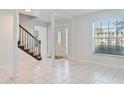 Bright foyer with tile flooring, decorative front door, staircase, and natural light streaming through a window at 4531 Lake Trudy Dr, St Cloud, FL 34769