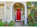 Inviting arched doorway with vibrant red door, surrounded by lush, tropical landscaping, and house number at 541 Rebecca Dr, St Cloud, FL 34769