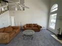 Large living room featuring high ceilings, a fireplace, and plush brown couches at 642 Riggs Cir, Davenport, FL 33897