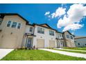 New construction townhomes featuring neat landscaping, attached garages and a bright blue sky at 947 Conch Rd, Davenport, FL 33896