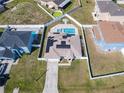 Aerial view of a fenced-in backyard with a pool, solar panels, a well-manicured lawn, and nearby houses at 152 Big Black Dr, Kissimmee, FL 34759