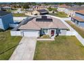 Aerial view of a single-story home featuring solar panels, a two-car garage, a manicured lawn, and a fenced yard at 152 Big Black Dr, Kissimmee, FL 34759