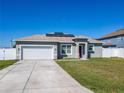 Charming single-Gathering home features a gray exterior, solar panels, a two-car garage, and a well-manicured lawn at 152 Big Black Dr, Kissimmee, FL 34759