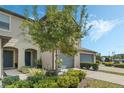 Townhome exterior featuring a lush green lawn, mature trees, and a two-car garage for convenient parking at 10871 Corsican St # 21, Orlando, FL 32824