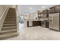 Open-concept kitchen and staircase, with stainless steel appliances and dark wood cabinets, and tile flooring at 10871 Corsican St # 21, Orlando, FL 32824