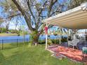 Serene backyard featuring a covered patio, lush lawn, mature tree, and a tranquil water view at 13223 Meadowlark Ln, Orlando, FL 32828