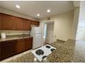 Galley kitchen with granite countertops, wood cabinets, and white appliances at 1916 Conway Rd # 11, Orlando, FL 32812