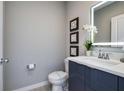 Stylish half-bathroom featuring a modern vanity, illuminated mirror, and decorative wall art at 4417 Le Reve Ct, Kissimmee, FL 34746