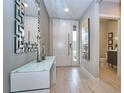 Modern foyer with light tile flooring, mirror, accent table, and a door leading to the bathroom at 4417 Le Reve Ct, Kissimmee, FL 34746