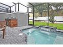 Screened-in pool area featuring a small waterfall feature, built-in barbecue and outdoor seating at 4417 Le Reve Ct, Kissimmee, FL 34746