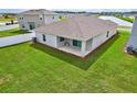 A view of the back of the house featuring a spacious yard and a small outdoor patio area at 64 Citrine Loop, Kissimmee, FL 34758