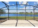 Screened-in patio boasts a stunning lake view and tiled flooring, perfect for outdoor relaxation and entertaining at 782 Vineyard Way, Poinciana, FL 34759