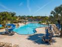 Stunning community pool featuring a water slide, lounge chairs, umbrellas, and palm trees at 8945 Cuban Palm Rd, Kissimmee, FL 34747