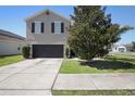 A two-story gray home with a black garage door and a well-maintained lawn with a tree at 1246 Maplebrook Dr, Lake Alfred, FL 33850