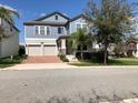 Two-story home featuring a brick driveway, a two-car garage, manicured landscaping, and a welcoming front porch at 15007 Night Heron Dr, Winter Garden, FL 34787