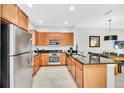Modern kitchen with stainless steel appliances, wooden cabinets, granite countertops, and an adjacent dining area at 2619 Corvette Ln, Kissimmee, FL 34746