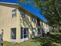 Back exterior featuring multiple screened patios, AC units, and lush greenery in a shared yard at 2706 Club Cortile Cir, Kissimmee, FL 34746