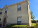 Side exterior view of two-story townhouse with a well-manicured lawn and blue sky at 2706 Club Cortile Cir, Kissimmee, FL 34746