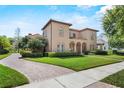 Beautiful stucco home featuring a lush lawn, arched windows, and a brick driveway leading to the house at 304 Acadia Ln, Celebration, FL 34747