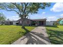 Single-story gray house with a well-manicured lawn and a mature tree providing shade on a sunny day at 4548 Cepeda St, Orlando, FL 32811