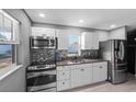 Modern kitchen with stainless steel appliances, white cabinets, granite counters, and mosaic backsplash at 4548 Cepeda St, Orlando, FL 32811