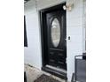 Close-up of front door showing a black door with oval glass insert and updated door bell at 4834 Ute St, Orlando, FL 32819