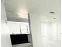 Bright entryway showcasing neutral walls, plank flooring, and an adjacent kitchen with black cabinets and stainless steel appliances at 817 Clay Blvd, Eustis, FL 32726
