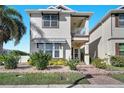 Charming two-story home featuring a small balcony, front garden with tropical plants, and brick-paved walkway at 8498 Powder Ridge Trl, Windermere, FL 34786