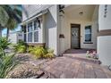 Inviting front porch features brick pavers, lush landscaping, and a decorative wreath on the gray front door at 8498 Powder Ridge Trl, Windermere, FL 34786