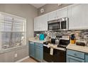 Galley kitchen with white and blue cabinets, stainless steel appliances, and tiled backsplash at 8534 Crystal Cove Loop, Kissimmee, FL 34747
