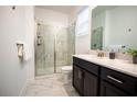 Bathroom featuring a glass-enclosed shower with marbled walls and a dark vanity at 1025 Leader St, Davenport, FL 33896