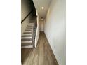 Bright hallway with hardwood flooring and staircase with modern dark wood railing at 12673 Yoshino Aly, Orlando, FL 32827